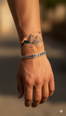 Hand with a tattoo of a mountain landscape and a chain bracelet on a blurred background