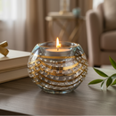 Candle in a decorative glass holder on a table with a blurred background