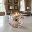 Decorative glass candle holder with a lit candle on a marble surface in a living room setting.