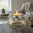Decorative glass candle holder with a lit candle on a table in a home setting.