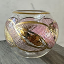 Hand-blown glass tea light holder with a pink glass body and gold leaf patterns in a geometric design.