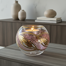 Decorative glass vase with a candle inside on a wooden surface, with vases and books in the background.