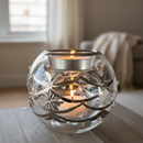 Decorative glass candle holder with a candle on a wooden surface.