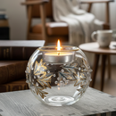 Decorative glass candle holder with a lit candle on a table in a cozy room.