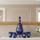 Set of blue ceramic decanter and cups on a shelf with a mirror in the background