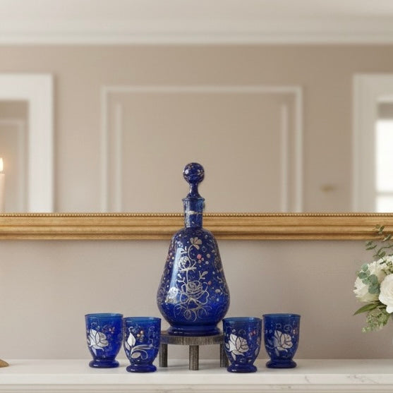 Set of blue ceramic decanter and cups on a shelf with a mirror in the background