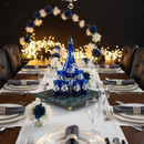 Elegant dinner table setting with blue decorative vase and floral arrangements, featuring a chandelier.