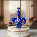 Set of blue glassware with floral designs on a marble tray in a modern living room.