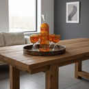 Wooden table with a decorative tray holding orange glassware and a tall orange vase.