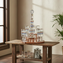Wooden table with decorative glasses and a photo frame in a room with a window and plant.