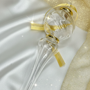 Decorative glass bottle with gold accents on a white and gold fabric background