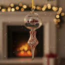 Decorative Christmas ornament hanging from a tree with a fireplace and lights in the background