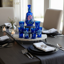 Dining table setting with blue floral glassware and a decorative bottle.