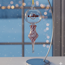 Decorative Christmas ornament with candy cane design on a stand against a blurred window background.