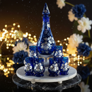 Decorative set with blue and white floral-patterned glasses on a marble stand against a blurred festive background.