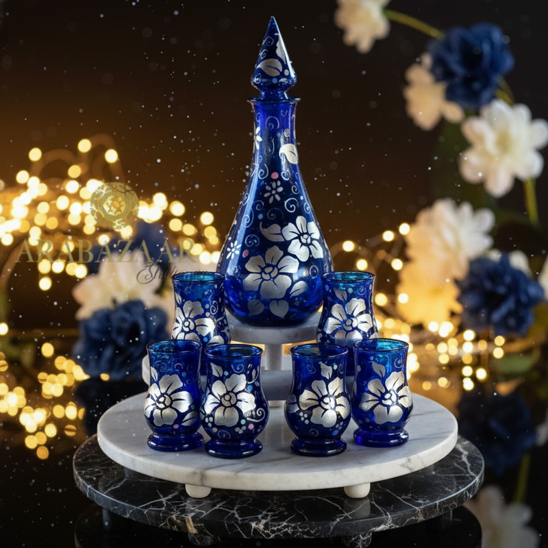 Decorative set with blue and white floral-patterned glasses on a marble stand against a blurred festive background.