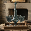 Set of blue glass decanter and goblets on a wooden tray with a stone fireplace background.