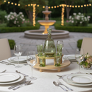 Elegant outdoor table setting with green glassware and a fountain in the background.