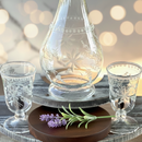 Decorative setting with glass carafe and shot glasses on a wooden stand with a blurred background