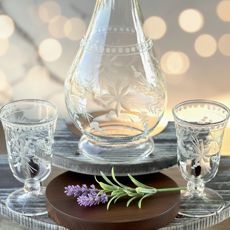 Decorative setting with glass carafe and shot glasses on a wooden stand with a blurred background