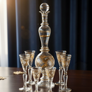 Decorative glass decanter and glasses on a wooden surface with a dark curtain background.
