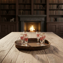 Tray with glasses on a wooden table in front of a fireplace and bookshelves