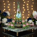 Decorative glass set with a decanter and glasses on a marble stand against a string light background.