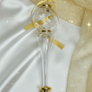 Decorative glass bottle with gold cap and ribbon on a white and gold fabric background