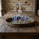 Set of blue and white glassware on a metal tray with a stone wall background