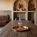 Decorative glass item on a copper tray on a wooden table with a rustic interior background.