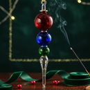Decorative smoking device with red, blue, and green glass beads on a dark background.