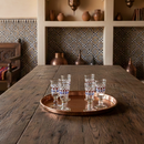 Wooden table with a tray of glasses in a rustic interior setting.