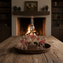 Decorative decanter and glasses on a wooden table with a fireplace in the background