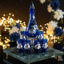 Set of blue glassware with white floral patterns on a dark background with blurred lights and flowers.