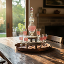 Decorative glass bottle with matching glasses on a wooden tray in a home setting.