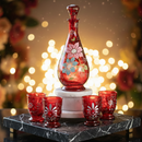 Decorative red glass set with floral patterns on a marble stand against a blurred festive background.
