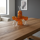 Set of orange glassware on a wooden table with a gray wall and framed picture in the background.