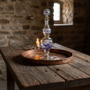 Decorative glass bottle with blue patterns on a wooden table in a stone-walled room.