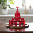 Red glass decanter and tumblers on a wooden tray in a kitchen setting.