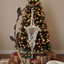 Decorative glass ornament with a branch in front of a Christmas tree and presents.