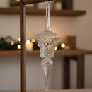 Clear glass hanging ornament on a wooden stand with a blurred indoor background