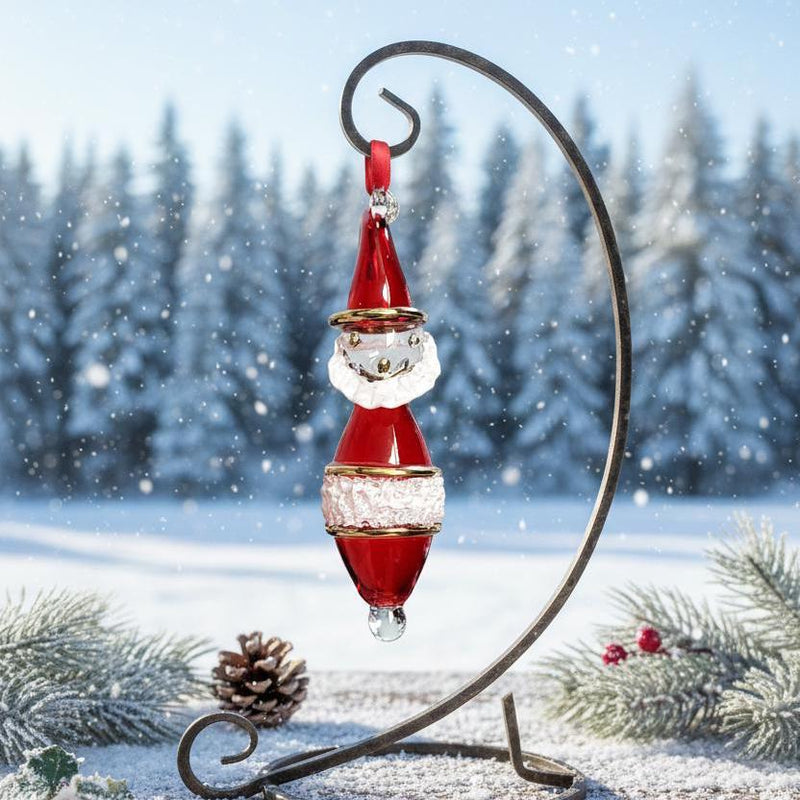 Decorative Christmas ornament of Santa Claus on a stand with a snowy landscape background.