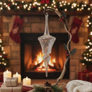 Decorative glass ornament hanging in front of a fireplace with Christmas stockings and lights.