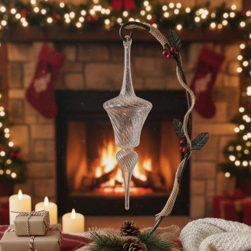 Decorative glass ornament hanging in front of a fireplace with Christmas stockings and lights.