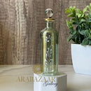 Decorative bottle on a white base with 'AraBazaar Gallery' branding, against a wooden background.