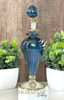 Blue glass bottle with gold accents on a white stand against a wooden background