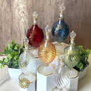 A collection of handblown glass perfume bottles with various colors and designs, featuring 14K gold trim.
