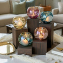 Decorative candles in glass holders on wooden blocks with a blurred living room background
